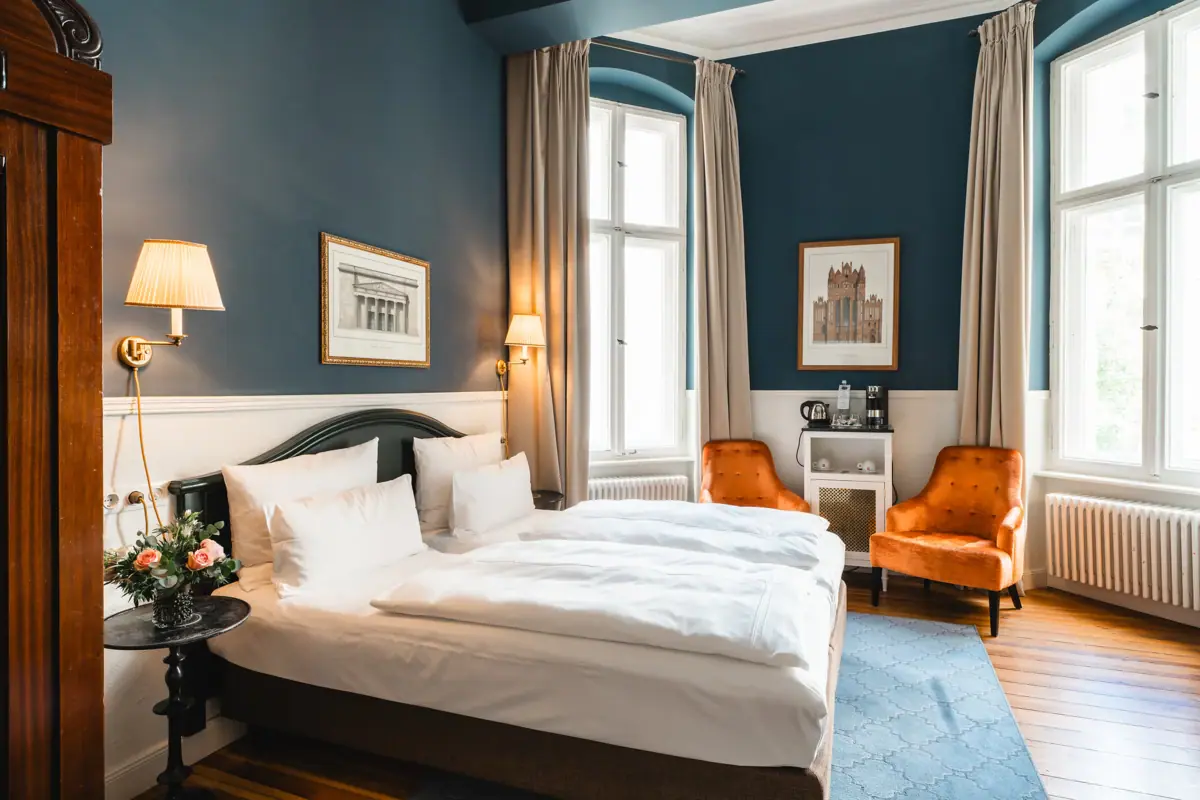 Ein Zimmer im HENRI Hotel Berlin mit zwei Betten und Stühlen.