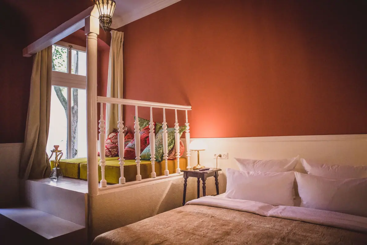 Ein Bett mit Kissen und einer Lampe in einem Zimmer.