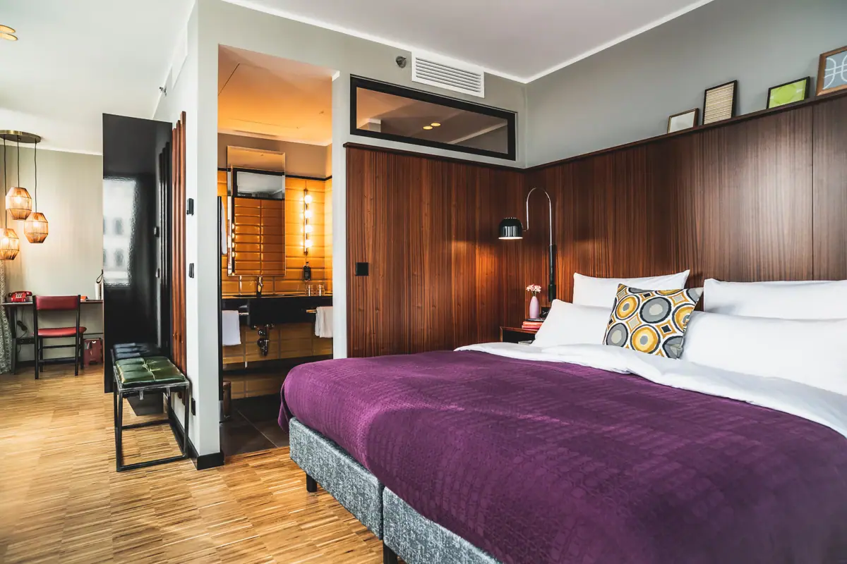 Schlafzimmer mit lila Bett und holzgetäfelten Wänden.