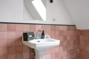 Badezimmer im HENRI Garmisch-Partenkirchen Waschbecken mit darüber hängendem Spiegel im Badezimmer.