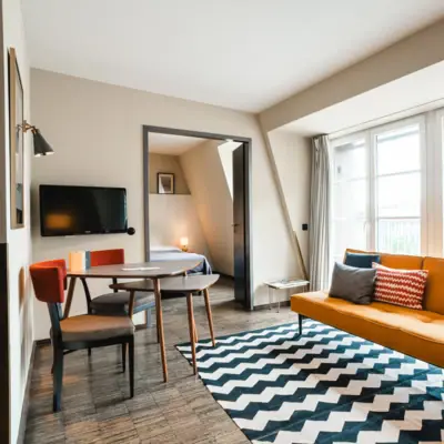 Gelbes Sofa vor einer Fensterfront und Tisch mit zwei Stühlen