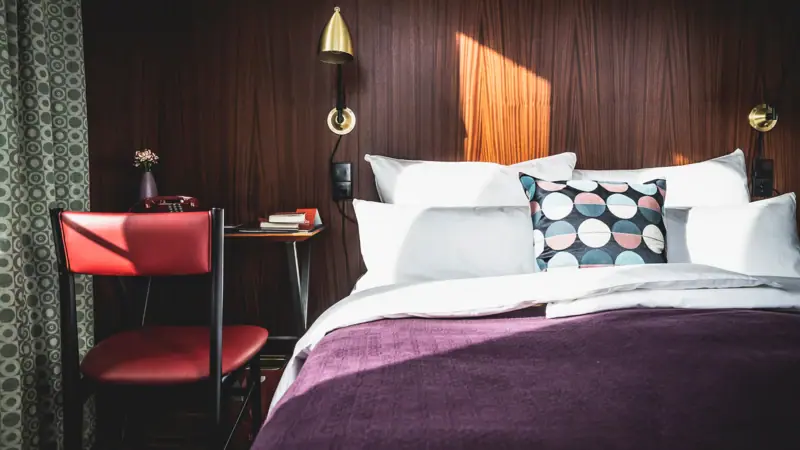 Bett mit Kissen und einem Schreibtisch davor im Hotelzimmer.