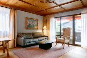 Suite im HENRI Garmisch-Partenkirchen Wohnzimmer mit einer Couch und einem Couchtisch.
