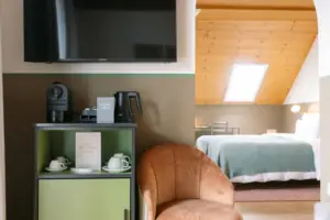 Suite im HENRI Garmisch-Partenkirchen Ein Zimmer mit einem Fernseher und einem Stuhl.