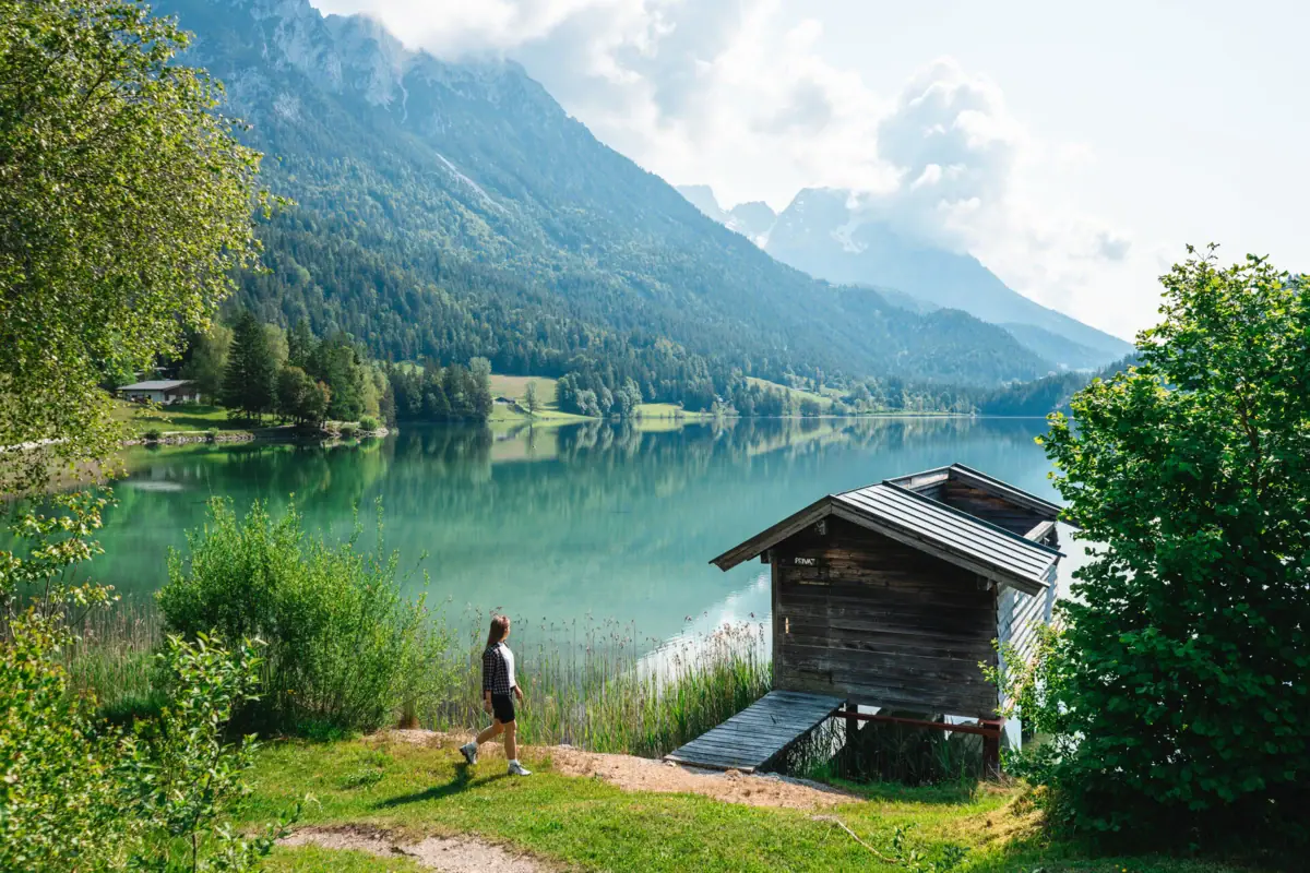 HENRI Partner Eine Person geht auf Gras neben einem See.