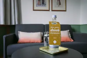 Ausziehbare Couch im HENRI Garmisch-Partenkirchen Eine Flasche Wasser auf einem Tablett.