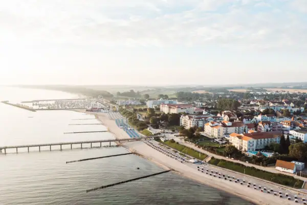 Stadt neben einem Gewässer aus der Vogelperspektive mit Himmel und Wolken.