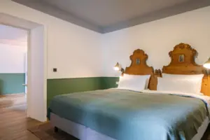 Zimmer im HENRI Garmisch-Partenkirchen Ein Bett mit zwei hölzernen Kopfteilen in einem Zimmer.