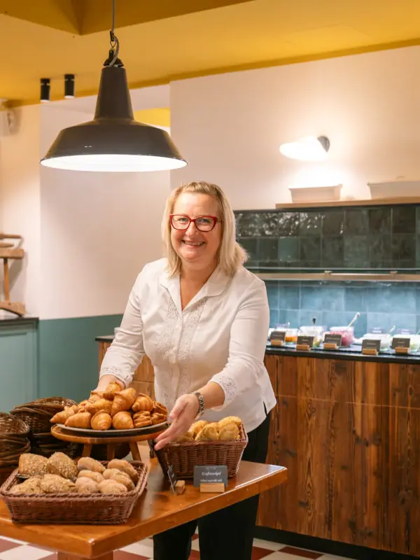 Frühstück im HENRI Garmisch-Partenkirchen Frau hält ein Tablett mit Essen in der Hand.