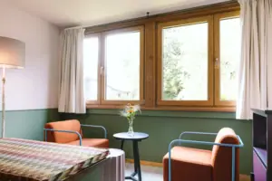Eine Sitzecke mit zwei Sesseln vor einem Fenster in dem Hotelzimmer Chambre im HENRI Hotel Garmisch-Partenkirchen.