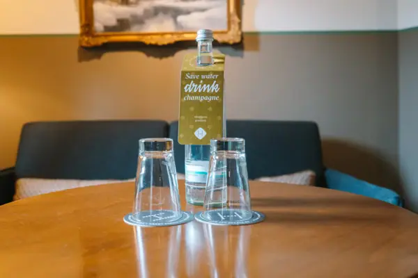 Wasserflasche und Gläser im HENRI Hotel Garmisch-Partenkirchen Eine Flasche und Gläser auf einem Tisch in einem Hotelzimmer des HENRI Hotel Garmisch-Partenkirchen.