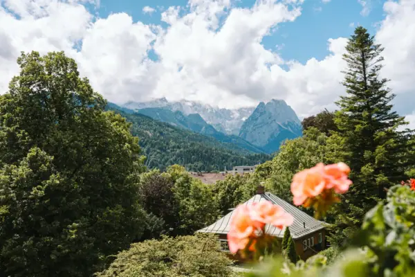Ausblick vom Balkon aus dem HENRI Hotel Garmisch-Partenkirchen mit Blumen und Bergen im Hintergrund.