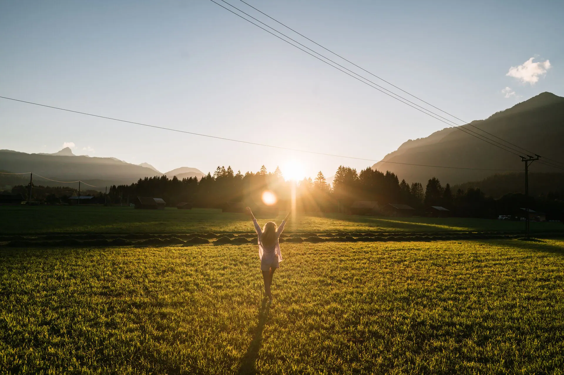 Eine Frau steht in einem Feld mit erhobenen Armen.