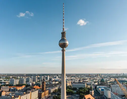 Fernsehturm Berlin mit großem spitzen Aufbau in der Mitte vor bewölktem Himmel.