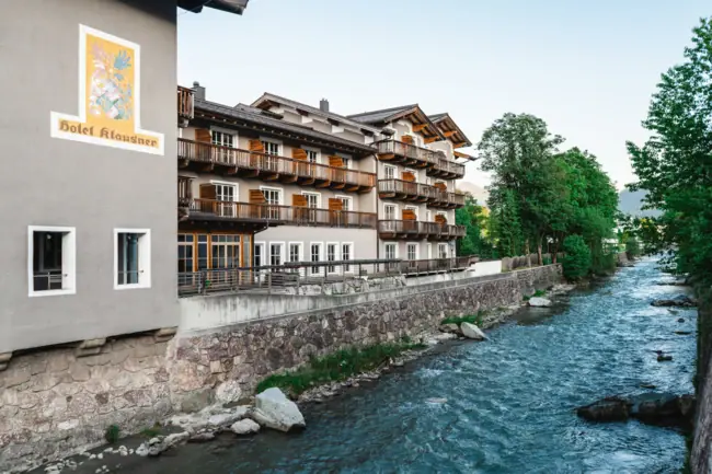 HERNI Kitzbühel Ein Fluss mit einem Gebäude und Bäumen.