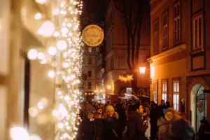 Weihnachtsbeleuchtung Eine Menschenmenge geht eine von Weihnachtslichtern beleuchtete Straße entlang.