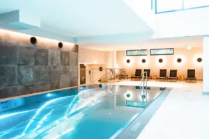 HENRI Kitzbühel Pool Innenpool mit Treppe und Stühlen.