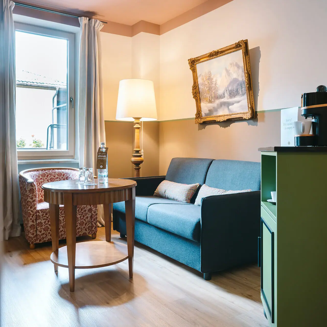 Wohnbereich in einem Hotelzimmer im HENRI Garmisch-Partenkirchen mit einem Sofa und einem Tisch.