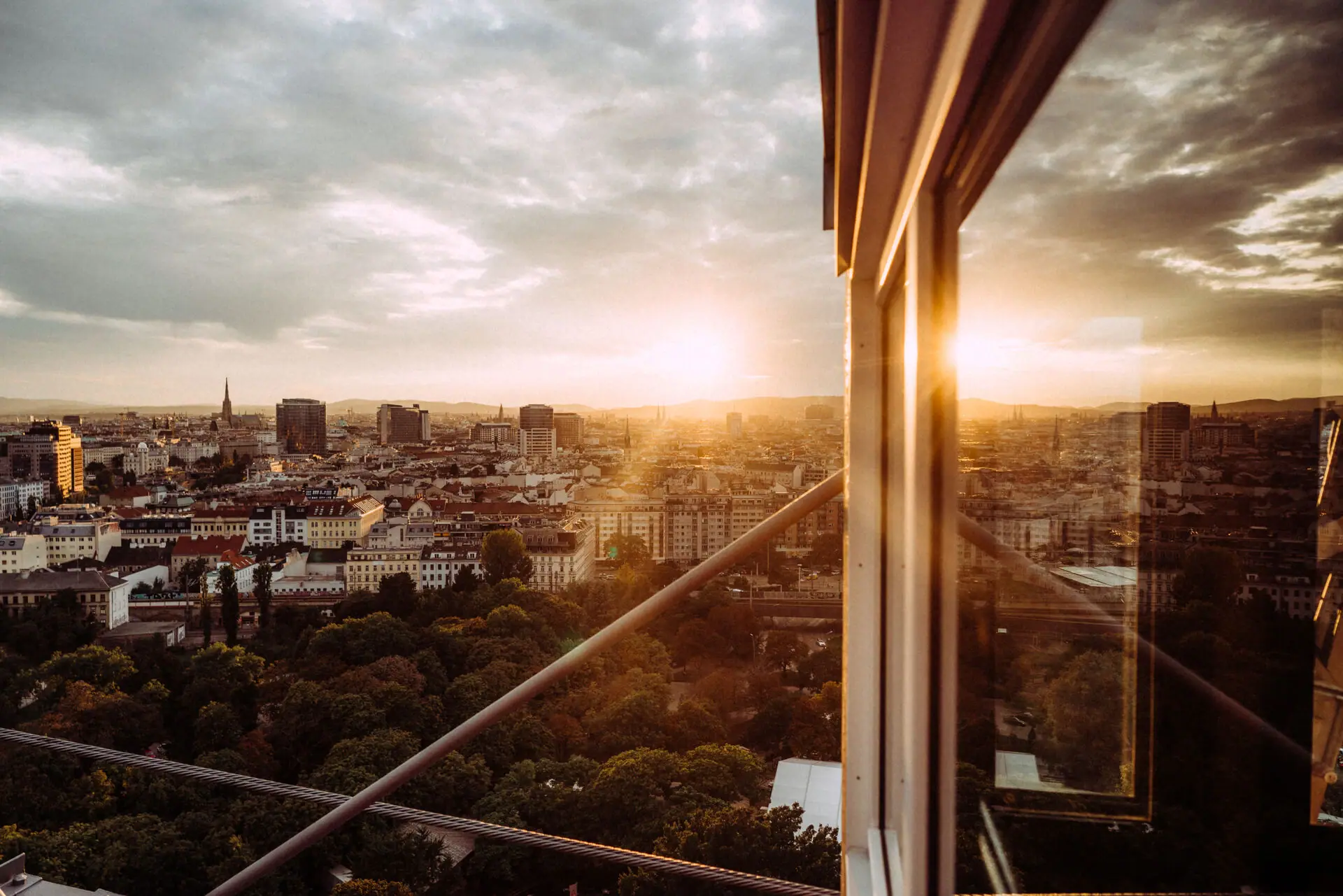 Blick auf eine Stadt durch ein Fenster mit Wolken und Gebäuden im Hintergrund.