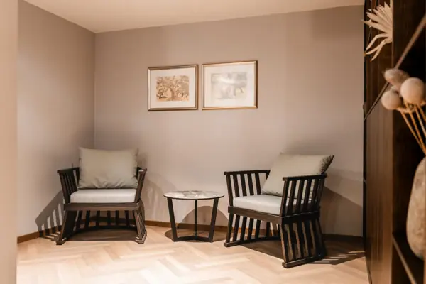 Ein Raum mit Stühlen und einem Tisch, ausgestattet mit einem Sofa, Holzboden und einem Kaffeetisch.