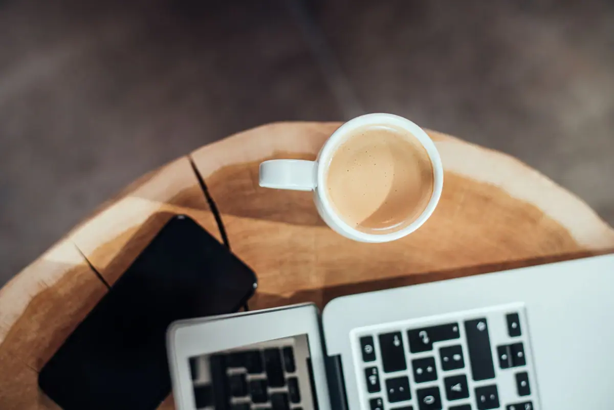 Eine Tasse Kaffee und ein Laptop auf einem Tisch.