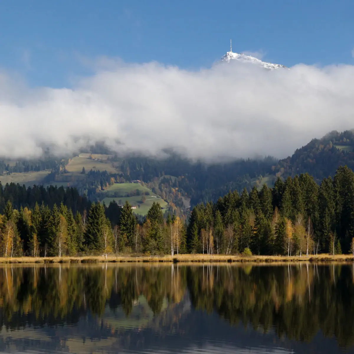 Kitzbühel Schwarzsee Ein See mit Bäumen und Bergen im Hintergrund.