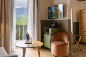 Wohnbereich im HENRI Garmisch-Partenkirchen Ein Zimmer mit einem Fernseher und einem Stuhl.