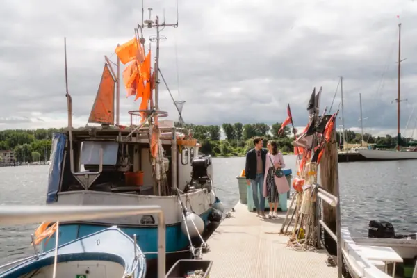 Fischerboote Ein Mann und eine Frau stehen auf einem Steg neben Booten im Hafen von Travemünde.