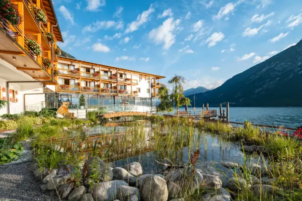 das aja Fürstenhaus am Achensee mit einem Teich und Bergen im Hintergrund.