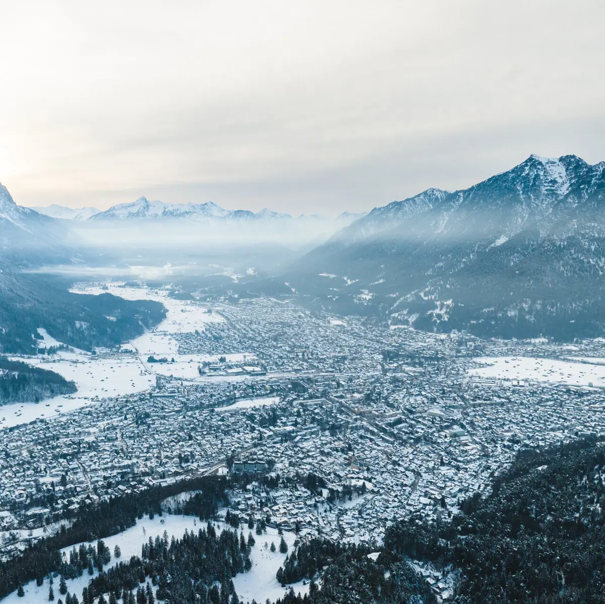 Eine verschneite Stadt mit Bergen im Hintergrund.