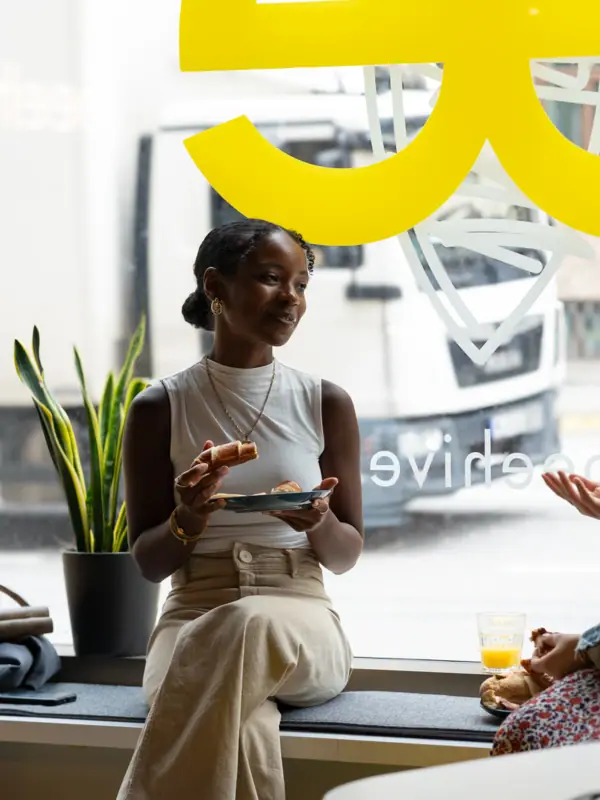 Eine Frau sitzt auf einem Fenstersims und isst.