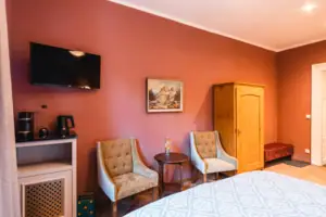 Ein Zimmer mit einem Bett, zwei Stühlen und stilvoller Inneneinrichtung.