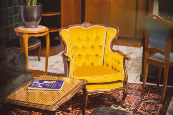 Lounge im HENRI Hotel Wien Gelber Stuhl und Tisch in einem Raum.