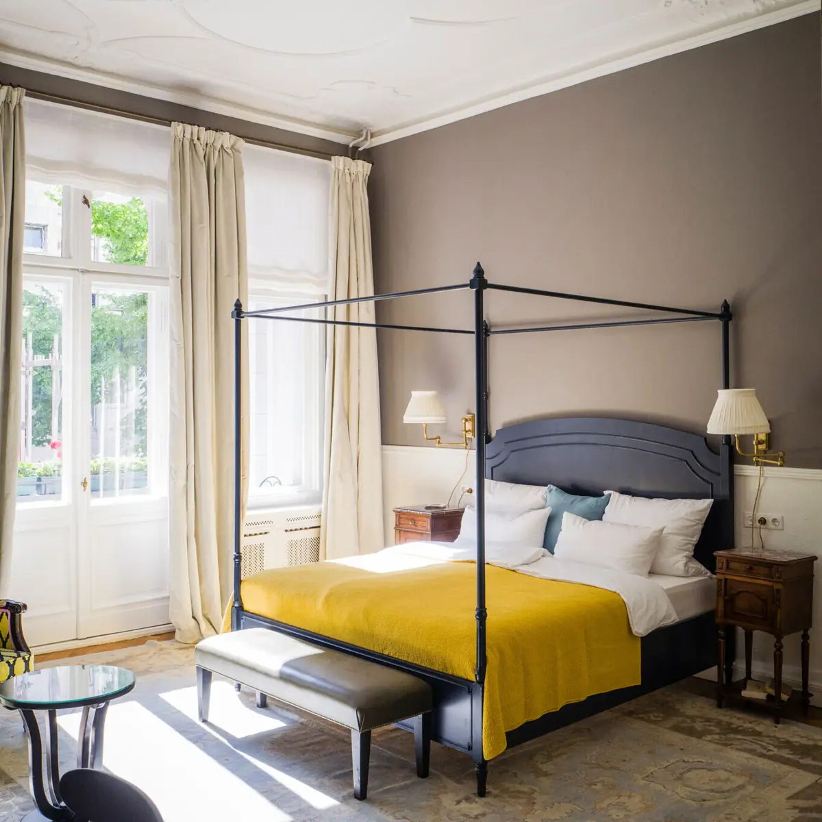 Ein Salon Zimmer im HENRI Hotel Berlin mit einem Bett und großen Fenstern.