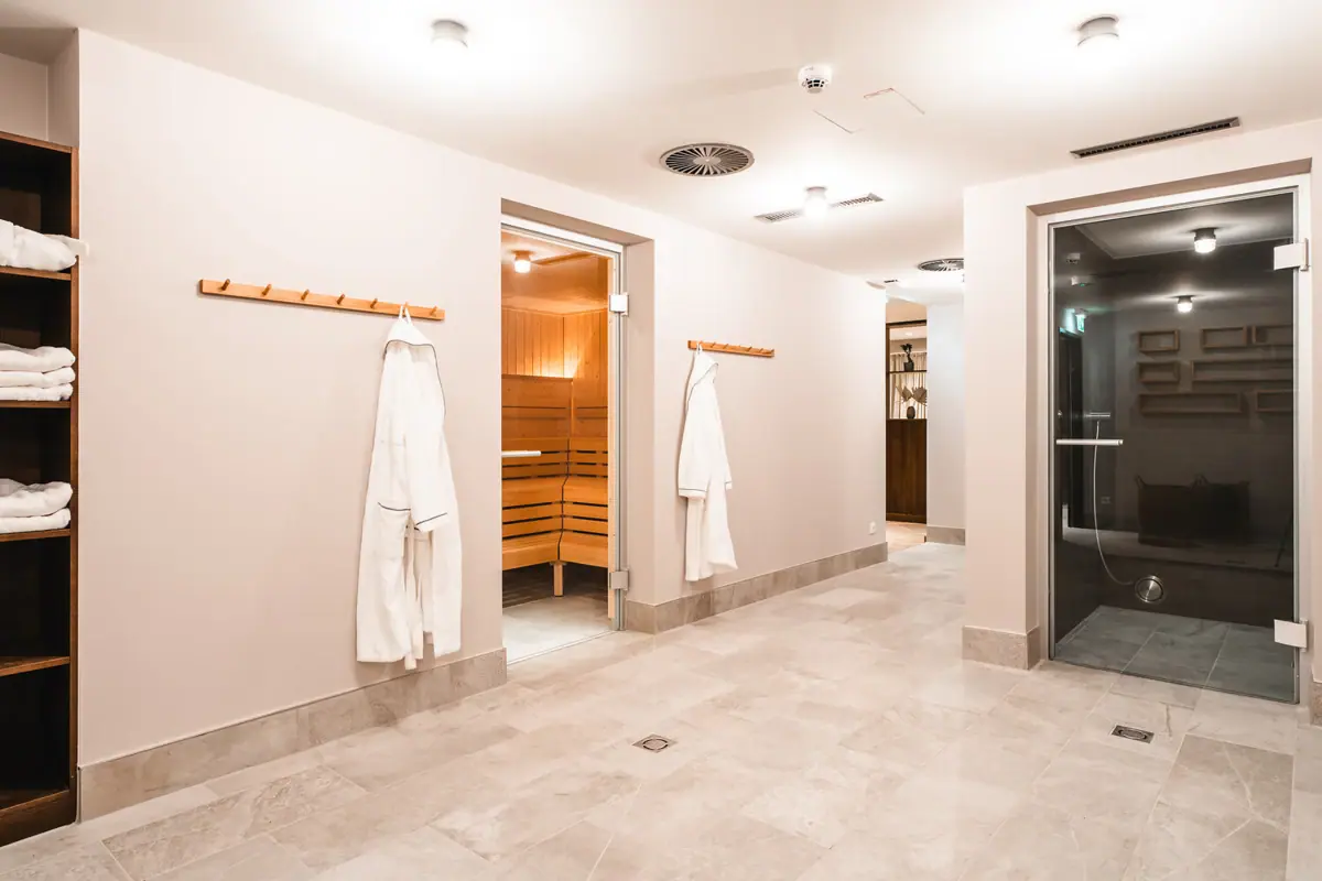 Ein Raum mit weißen Bademänteln und einer Sauna.