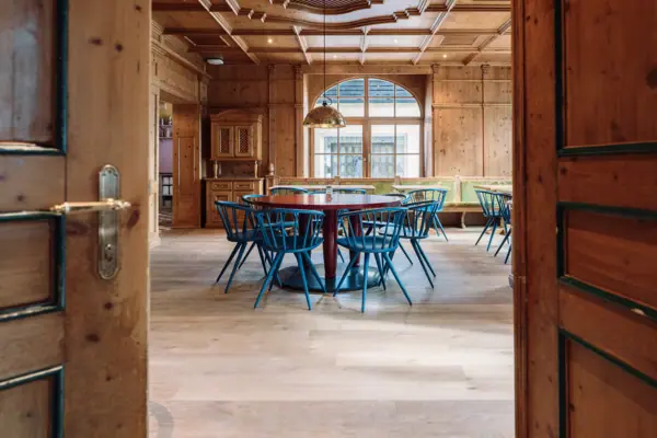 Ein Raum mit einem runden Tisch und blauen Stühlen.