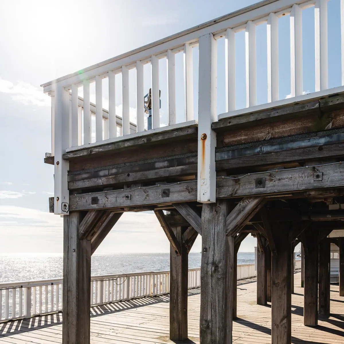 Holzdeck mit weißen Geländern an einem sonnigen Tag