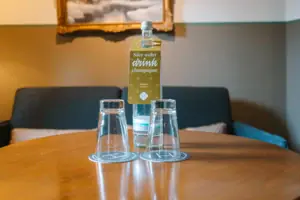 Wasserflasche und Gläser im HENRI Hotel Garmisch-Partenkirchen Eine Flasche und Gläser auf einem Tisch in einem Hotelzimmer des HENRI Hotel Garmisch-Partenkirchen.