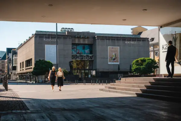 Kunsthalle Düsseldorf Zwei Frauen gehen auf einem Platz spazieren.