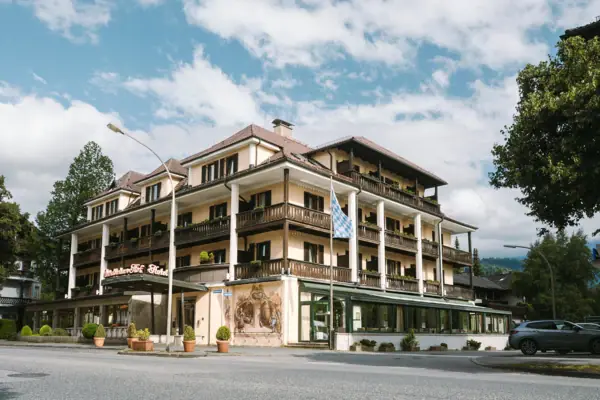 Außenansicht HENRI Hotel Garmisch-Partenkirchen mit Bäumen und einer Straße.