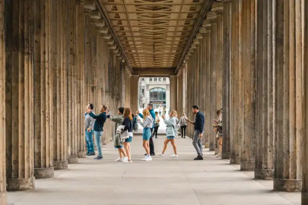 Perspektivische Ansicht des historischen Kolonnadengangs auf der Berliner Museumsinsel mit Touristen zwischen den imposanten Steinsäulen.