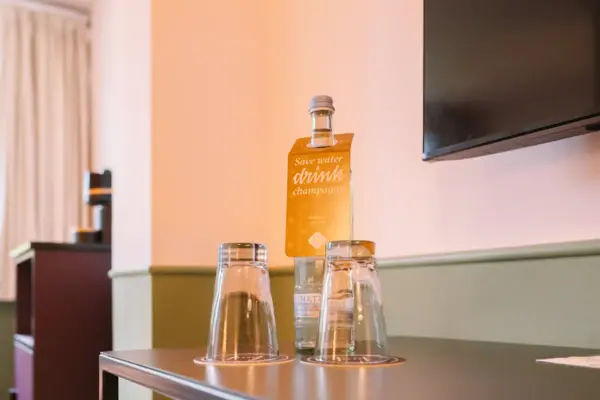 Wasserflasche und Gläser im HENRI Hotel Garmisch-Partenkirchen Eine Flasche und Gläser auf einem Tisch in einem Hotelzimmer des HENRI Hotel Garmisch-Partenkirchen.