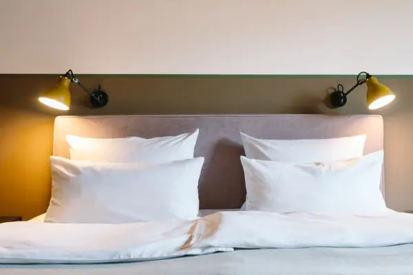 Hotelzimmer HENRI Hotel Garmisch-Partenkirchen Ein Bett mit weißen Kissen und einer Lampe in einem Hotelzimmer im HENRI Hotel Garmisch-Partenkirchen.