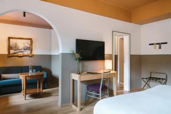 Hotelzimmer HENRI Hotel Garmisch-Partenkirchen Ein großes Hotelzimmer im HENRI Hotel Garmisch-Partenkirchen mit einem Duchgang vom Schlaf- in den Wohnbereich.