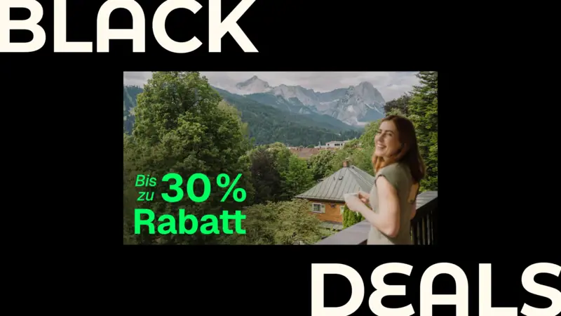 Eine Frau steht auf einem Balkon mit Blick auf eine Bergkette.