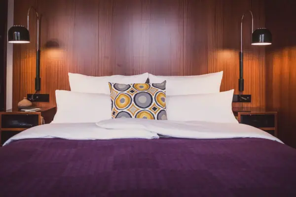 HENRI Düsseldorf Ein Bett mit Kissen und einer Lampe.