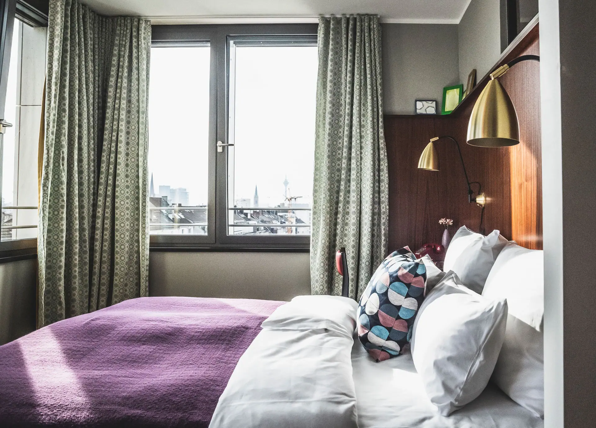 Ein Bett mit Kissen und einer Lampe in einem Raum mit Fenstern.