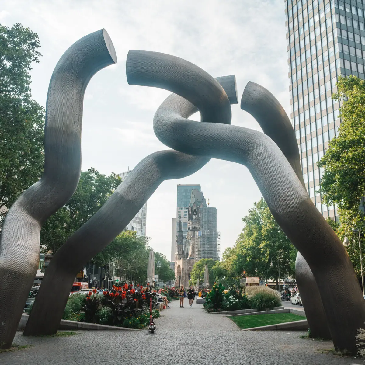 Skulptur aus verdrehten Metallstücken in einer Stadtumgebung.