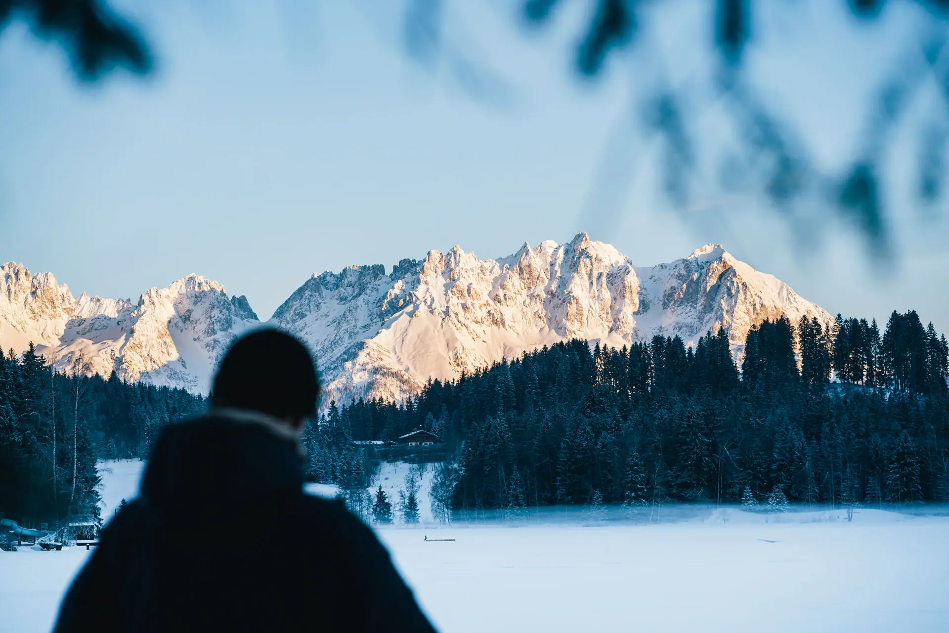 Eine Person steht vor einem schneebedeckten Berg.