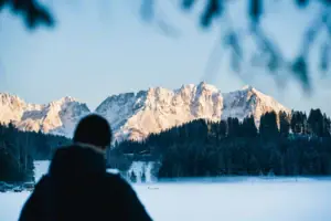 Eine Person steht vor einem schneebedeckten Berg.